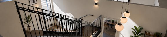 A black metal staircase with a white railing and a white table with a plant on it.
