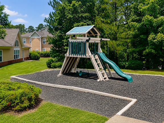 A playground with a green slide and a wooden structure.