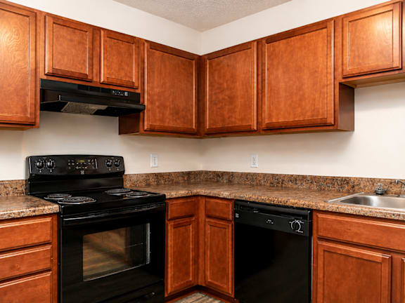 A kitchen with wooden cabinets and black appliances.