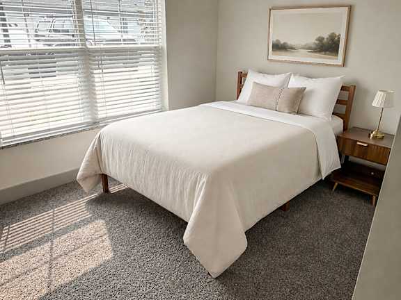 A bedroom with a large bed and a painting on the wall.