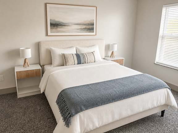 A bedroom with a large bed and a painting on the wall.