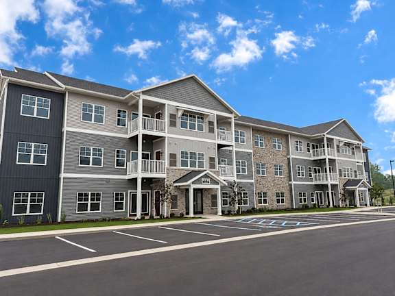 A large apartment complex with a parking lot in front.