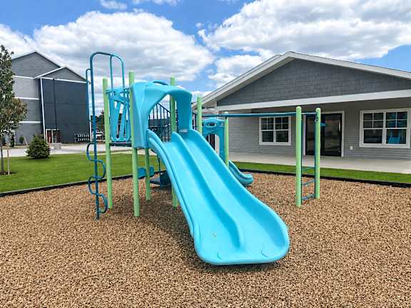 A blue slide in a playground with a green metal frame.