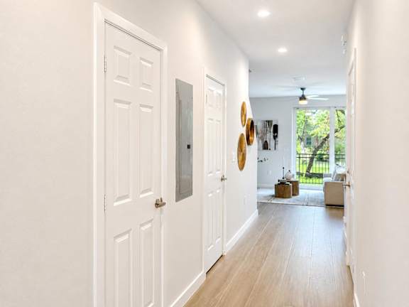 A hallway with white doors and a ceiling fan.