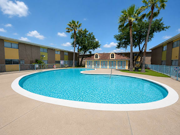 A round swimming pool in front of a building with a fence around it.