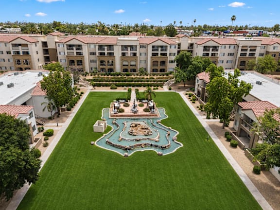 A view of a housing complex with a green lawn and palm trees.
