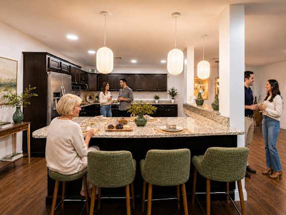 A group of people are gathered around a kitchen island.