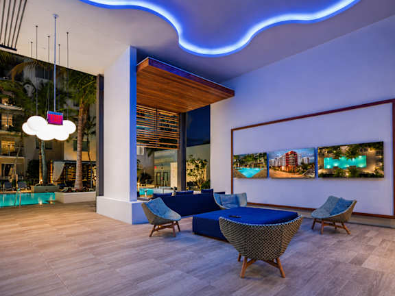 A modern living room with a blue sofa and a large painting on the wall.