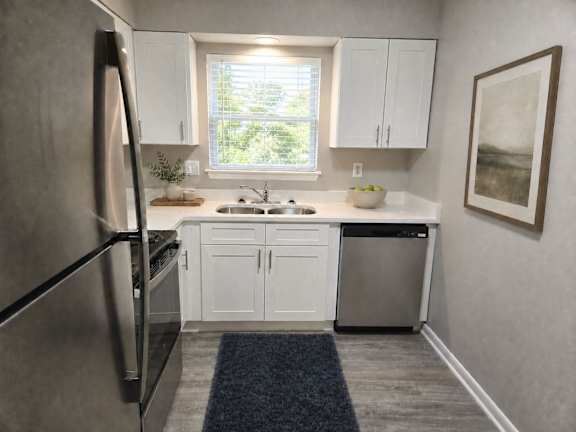 A modern kitchen with white cabinets and a stainless steel refrigerator.