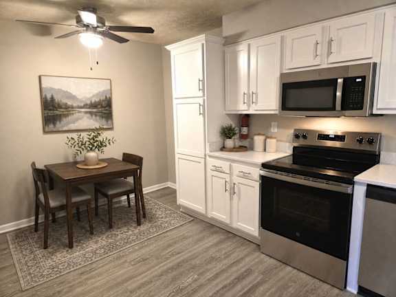 A kitchen with a table and chairs and a painting of a lake on the wall.
