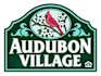 A green sign with a cardinal and the words "Audubon Village" on it.