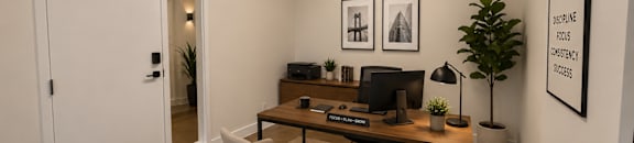 A room with a desk, chairs, and pictures on the wall.