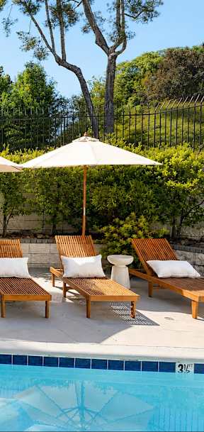 A pool with a diving board and lounge chairs.