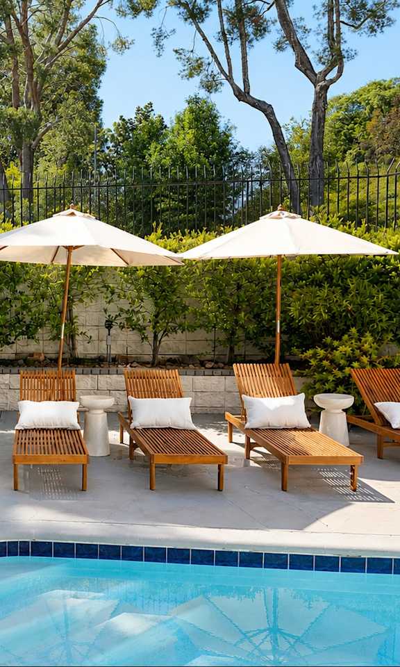 A pool with a diving board and lounge chairs.