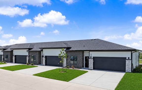 A modern white house with a black door and windows is surrounded by greenery. at Callaway at Holland Pointe Apartments, Iowa