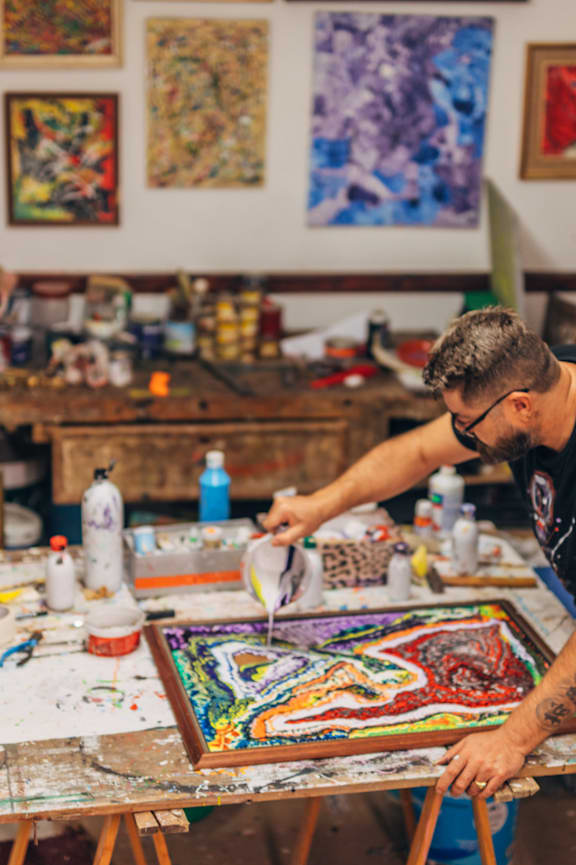 a man working on a painting in a studio with paintings on the wall