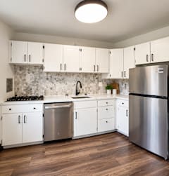 A kitchen with white cabinets and a stainless steel refrigerator.