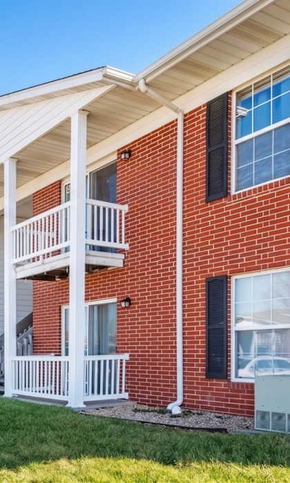 A row of red brick apartment buildings with white balconies.