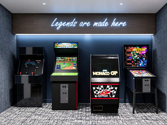 A row of arcade games including Monaco GP and Golden Tee 99.