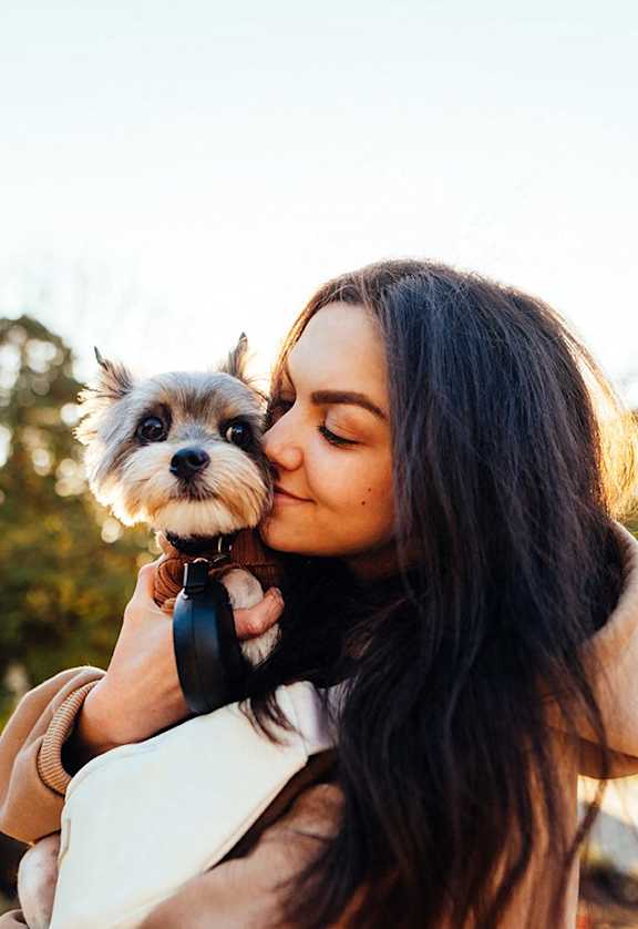 a woman kissing a small dog in a bag