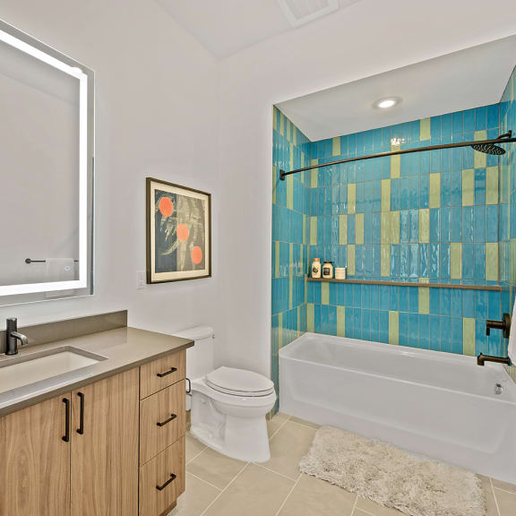 A bathroom with a blue tiled shower and a white toilet. at Four23/Hoge, Cincinnati, OH, 45226