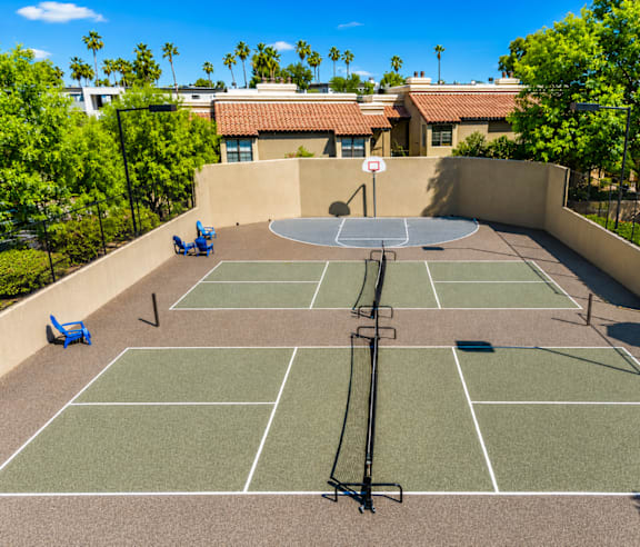 A tennis court with a net and two chairs.