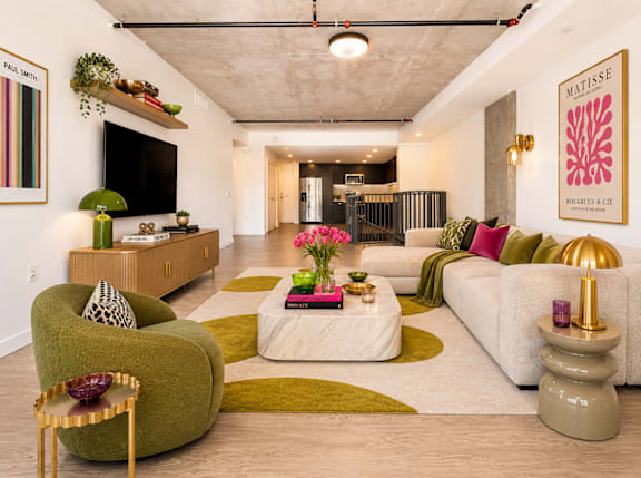 A living room with a white couch, green armchair, and a coffee table with a vase of flowers on it at Fusion Hollywood.