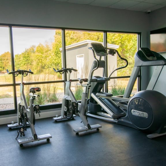 a gym with exercise machines and a large window with a view of a golf course