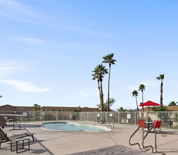 A pool area with sun loungers and palm trees.