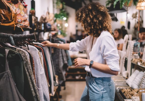 Woman Looking Through Clothing Rack in Clothing Store