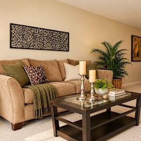 A living room with a couch, coffee table, and a mirror.