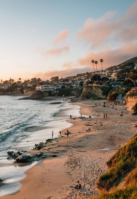 people on the beach near the water at sunset