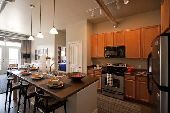 A kitchen with wooden cabinets and a black oven at The Foundry Apartments , South Bend, IN, 46617