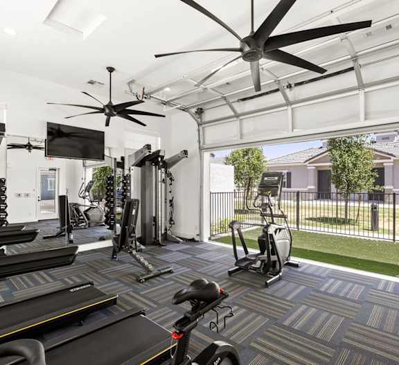 A gym with treadmills, elliptical machines, and a fan at Zora Encanto, Phoenix, AZ 85035