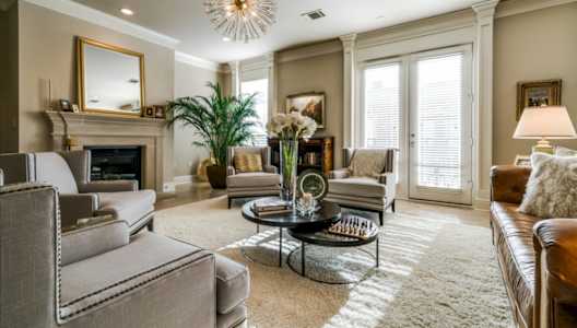 A living room with a grey couch, a coffee table, a fireplace, and a chandelier.