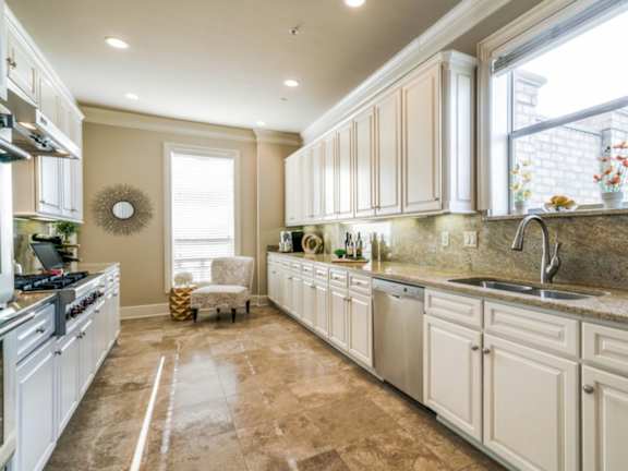 A kitchen with white cabinets and a tiled floor.