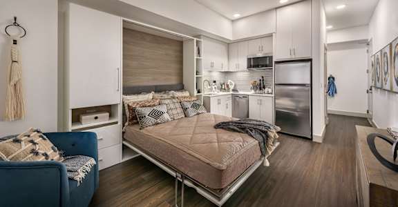 a bedroom with a bed and a kitchen