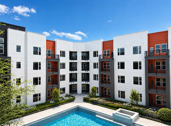 A modern apartment complex with a pool in the courtyard.