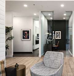 A grey chair sits in a room with a glass wall.