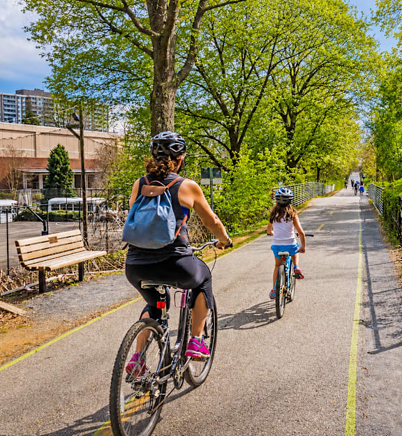 Two people riding bikes on a paved trail in a park.