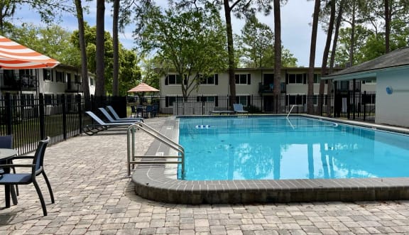 a resort style swimming pool with chairs and trees