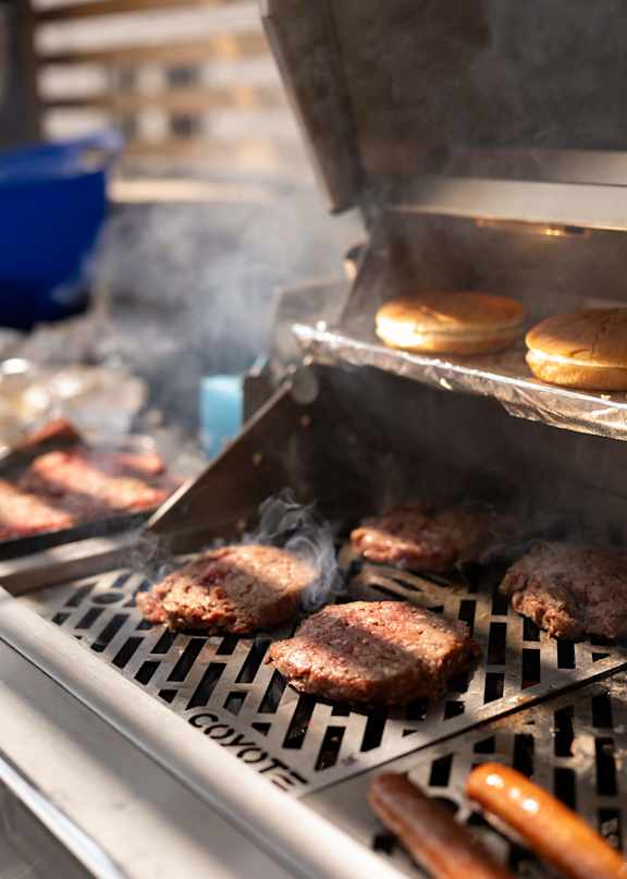 A grill with hamburgers and hot dogs cooking on it.