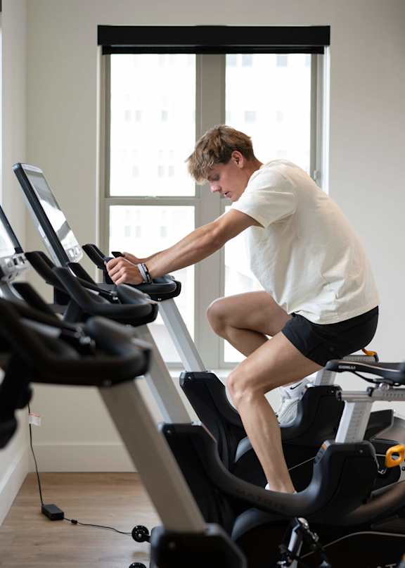 A man is exercising on a stationary bike in a bright room.