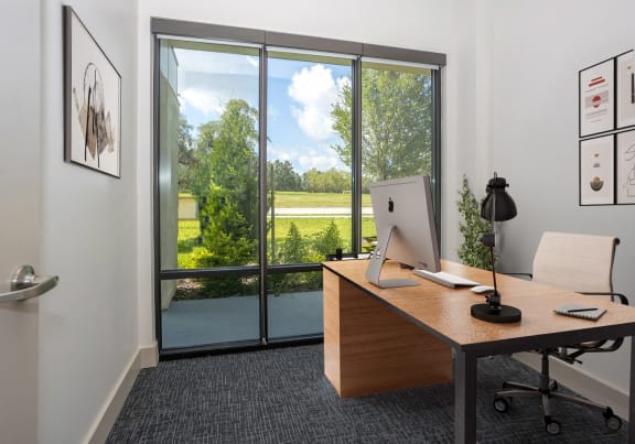 a desk with a computer on it in a room with a window