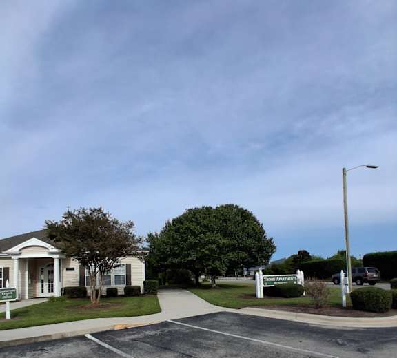 A parking lot in front of a building with a sign that says "Greenwood".