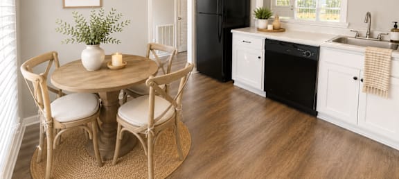 A kitchen with a round table and chairs, a black refrigerator, and a window with blinds.