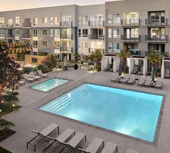 an apartment building with a pool and lounge chairs