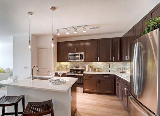 A modern kitchen with a white island and dark brown cabinets.