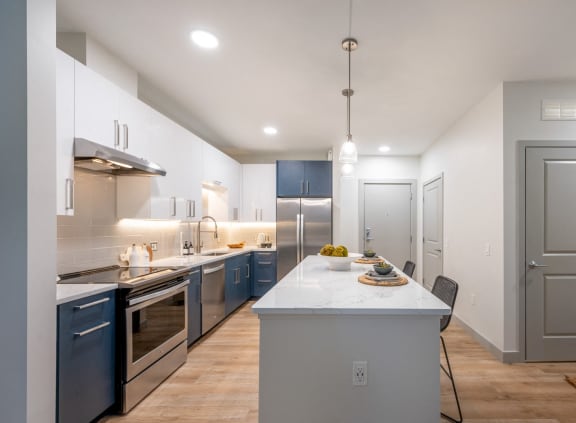 a large kitchen with a white counter top and blue cabinets