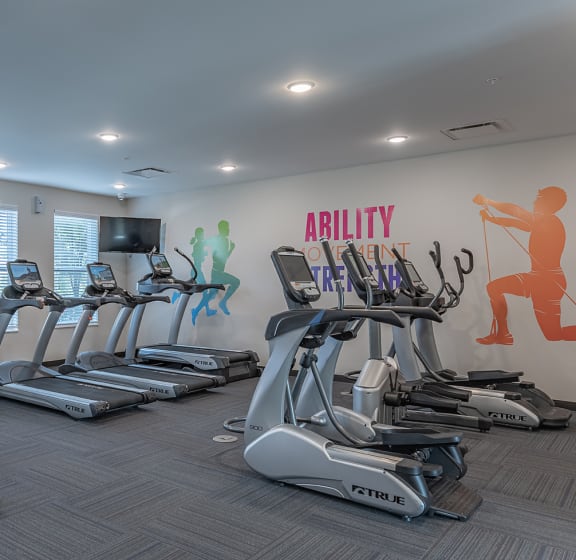 a gym with treadmills and cardio equipment and a wall graphic of running simulations at DeSales Flats Apartments*, Cincinnati, 45206